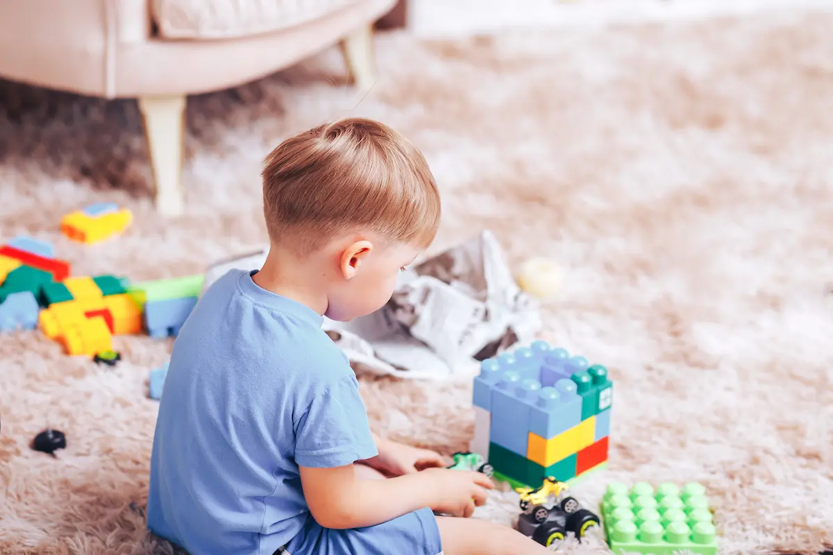 Bumble Bee. Little boy plays with designer and toy cars in a blue T-shirt on the floor