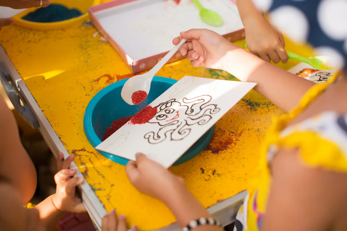 Happy tots. A child draws with colored sand picture. Cartoon characters