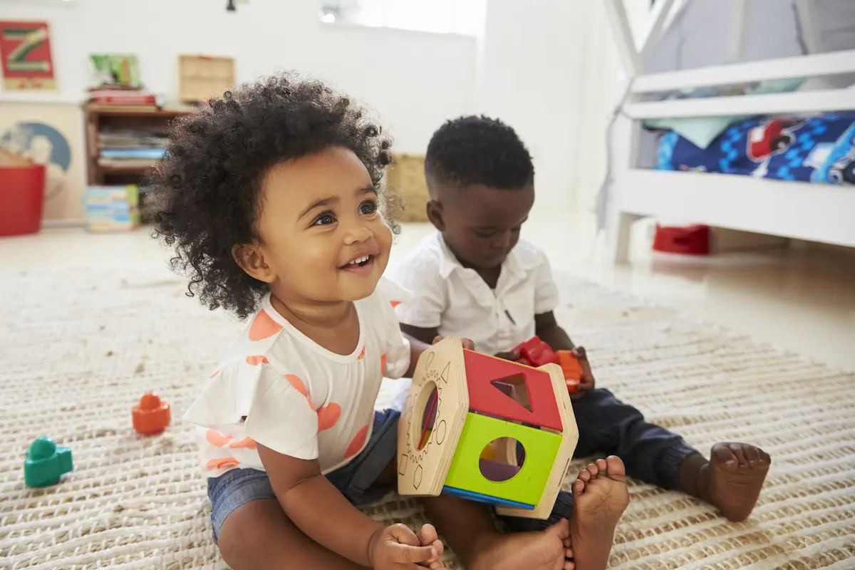 Punnagai. Baby Boy And Girl Playing With Toys In Playroom Together